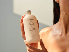 A person holds a matte bottle labeled KEE Liquid Marine Collagen - Limoncello against a neutral background.
