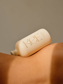 KEE Liquid Marine Collagen - Limoncello bottle rests on bare skin, softly lit against a neutral background.