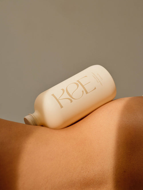 KEE Liquid Marine Collagen - Limoncello bottle rests on bare skin, softly lit against a neutral background.