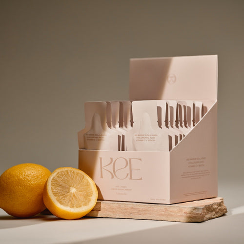 KEE Liquid Marine Collagen Sachet - Limoncello with fresh lemon on a wooden board, set against a neutral backdrop.