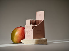 A pink box of KEE Liquid Marine Collagen Sachet - Mango Sorbet is displayed by a mango on a stone slab.