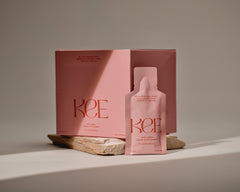 KEE Liquid Marine Collagen Sachet - Peach Elderflower with Biotin, box and sachet on stone against a neutral background.