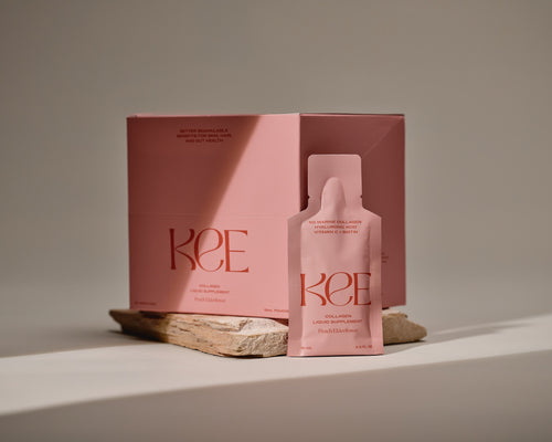 KEE Liquid Marine Collagen Sachet - Peach Elderflower with Biotin, box and sachet on stone against a neutral background.